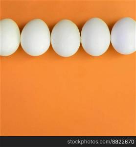 A few white easter eggs on a bright orange background