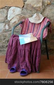 A figure made of female clothing on the chair with a map in the background of the stone wall.