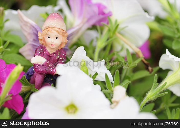 A figurine of a fairy displayed amongst white and pink petunias