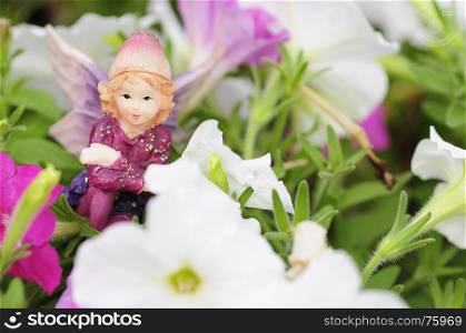 A figurine of a fairy displayed amongst white and pink petunias