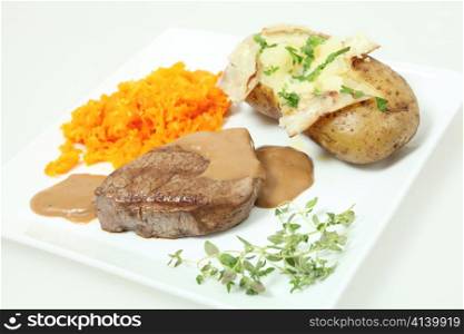 A filet mignon tenderloin steak served with grated braised carrots and a baked potato. Garnished with chopped parsley and a sprig of fresh thyme