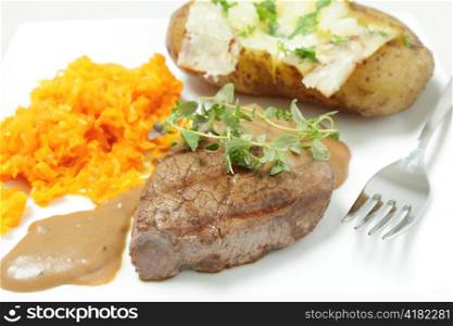 A filet mignon tenderloin steak served with grated braised carrots and a baked potato. Garnished with chopped parsley and a sprig of fresh thyme, with a fork
