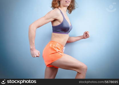 A fir young woman in workout clothes is in a running pose