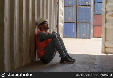 A fired man. Stressed upset depressed worried disappointed worker working in cargo container warehouse industry factory site in export, import, and transportation concept. Business people.