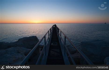 A fishing platform extendes out over Lake Michigan as the sun hits the horizon