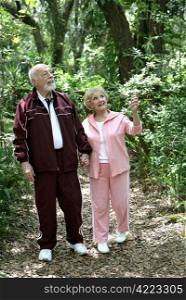 A fit retired senior couple walking together in the woods.