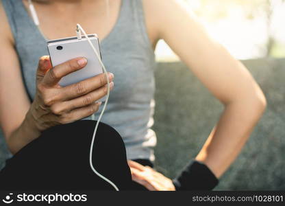 A fitness girl is sitting using a smartphone.