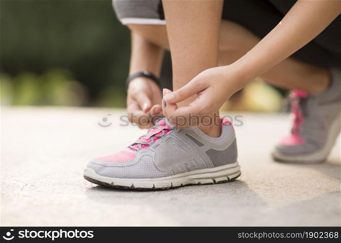 A fitness woman tying her shoes on the lawn