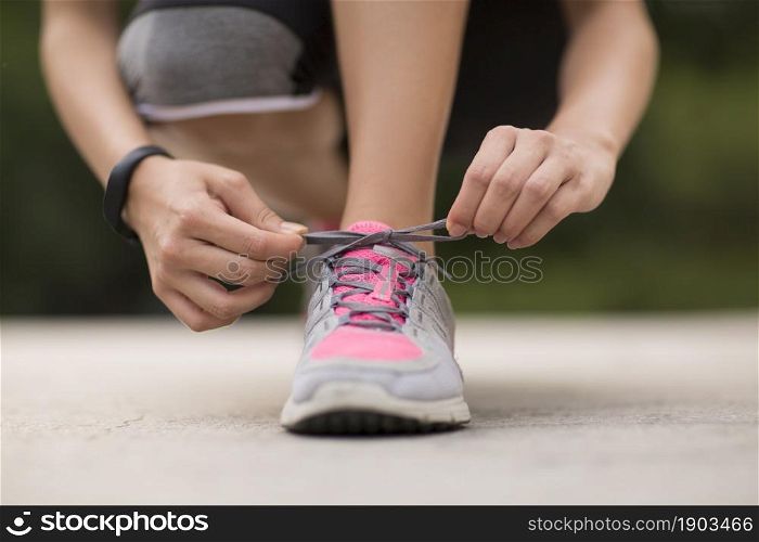 A fitness woman tying her shoes on the lawn