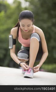 A fitness woman tying her shoes on the lawn