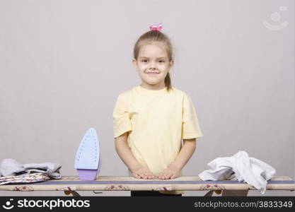 A five year old girl playing in a housewife, and stroking things iron