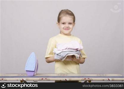 A five year old girl playing in a housewife, and stroking things iron