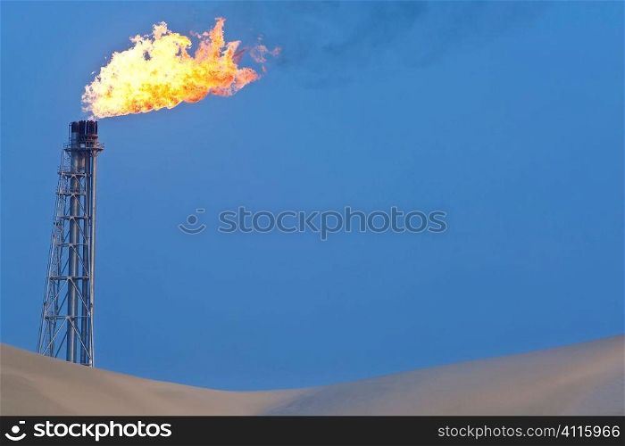 A flare stack burning off excess gas at an oil refinery in the desert