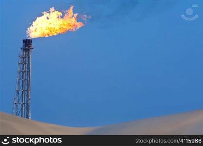 A flare stack burning off excess gas at an oil refinery in the desert