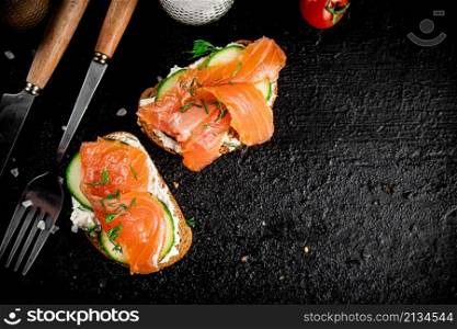 A flavorful salmon sandwich on the table. On a black background. High quality photo. A flavorful salmon sandwich on the table.