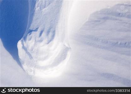 A foot print from a bolar bear with loose snow blown away