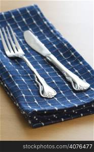 A fork and knife on a blue tablecloth