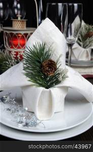 A fragment of a Christmas table setting napkin decorated with pine branches pinecone