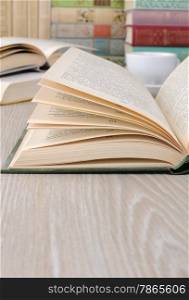 A fragment of an open book on the table among other books