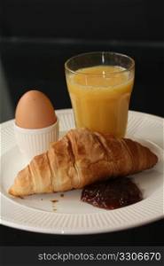 A French breakfast: a croissant with marmelade, orange juice and an egg