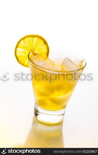 A fresh and tasty cocktail with alcohol and lemon on a glass table with yellow reflection