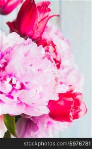 A fresh bouquet of pink peonies and tulips on a blue wooden background. Peonies and tulips