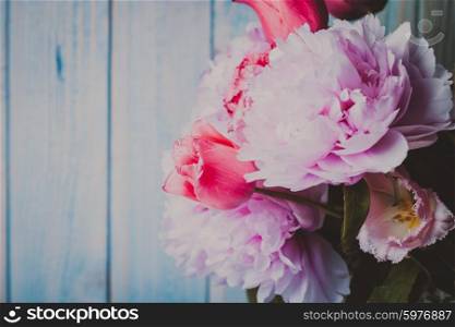 A fresh bouquet of pink peonies and tulips on a blue wooden background. Peonies and tulips