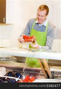 A fresh fish counter in a grocery store - clerk with a lobster