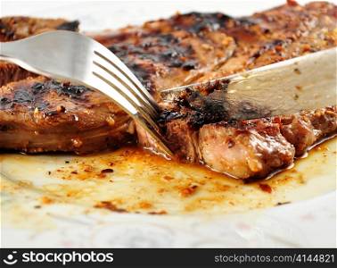 a fresh grilled steak on a plate ,close up, with fork and knife