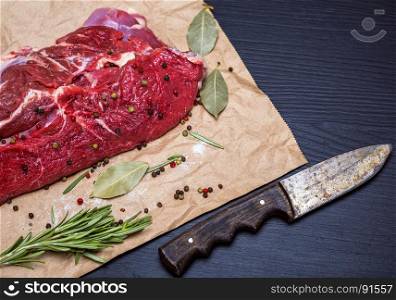 a fresh piece of beef on a brown sheet of paper, next to a knife