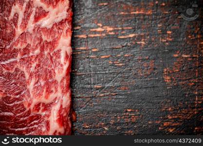 A fresh piece of raw steak. Against a dark background. The texture of the meat. High quality photo. A fresh piece of raw steak.