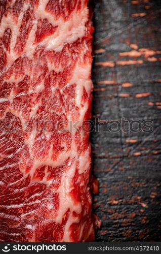 A fresh piece of raw steak. Against a dark background. The texture of the meat. High quality photo. A fresh piece of raw steak.