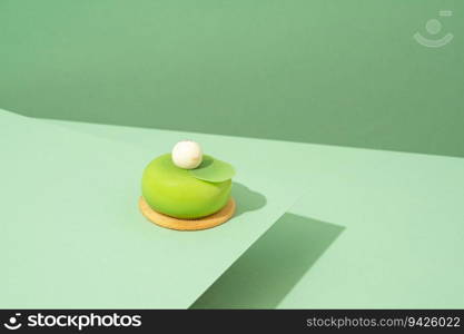 A freshly baked pastry with green and white icing, sitting atop a green-hued surface. A green pastry with white icing sitting on top of a green surface