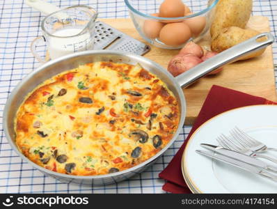 A freshly cooked Spanish omelet or tortilla de patates still in the pan, with essential ingredients behind