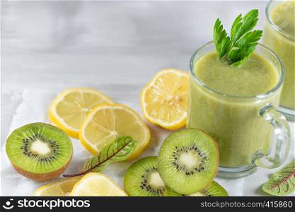 A freshly prepared smoothie of kiwi, lemon, orange and parsley on a cement table. Diet vegetarian food. Raw foods