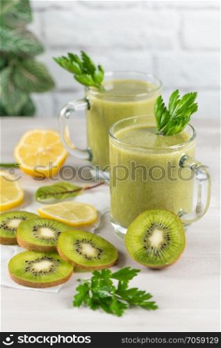 A freshly prepared smoothie of kiwi, lemon, orange and parsley  on a cement table. Diet vegetarian food. Raw foods