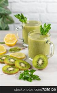 A freshly prepared smoothie of kiwi, lemon, orange and parsley  on a cement table. Diet vegetarian food. Raw foods