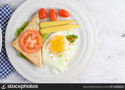 A fried egg laying on a toast, topped with pepper seeds with carrots, baby corn and spring onions.