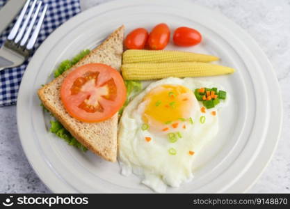 A fried egg laying on a toast, topped with pepper seeds with carrots, baby corn and spring onions.