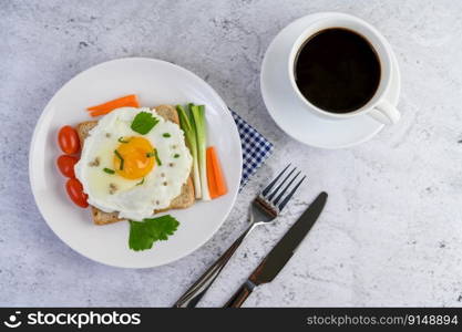 A fried egg laying on a toast, topped with pepper seeds with carrots and spring onions.