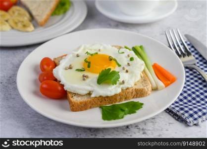 A fried egg laying on a toast, topped with pepper seeds with carrots and spring onions.