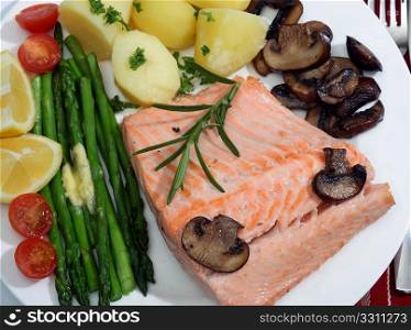A fried salmon steak, served with mushrooms, asparagus, cherry tomatoes and new potatoes, topped off with a sprig of rosemary