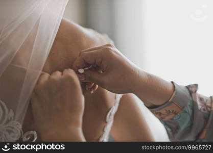 A friend helps the bride to put on a wedding dress.. The process of buttoning a wedding dress 2452.