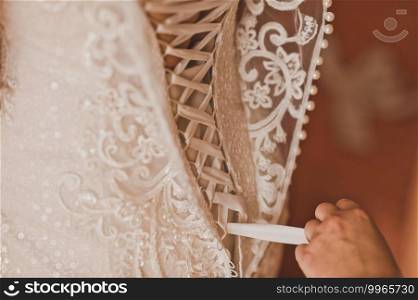 A friend helps the bride to wear a wedding dress.. The process of lacing the brides wedding dress 2218.