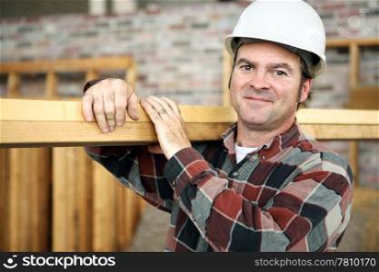 A friendly appealing construction worker in classic pose, carrying planks on the jobsite. Model is actual construction worker. Authentic and accurate content depiction.