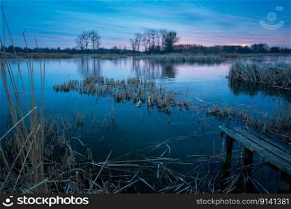 A frozen lake and an old wooden bridge, evening view