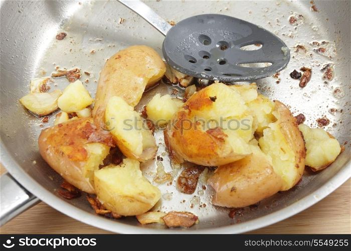 A frying pan with crushed potatoes cooked in butter and olive oil with some garlic