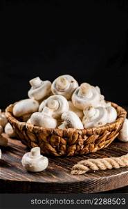A full basket of mushrooms on a wooden tray. On a black background. High quality photo. A full basket of mushrooms on a wooden tray.