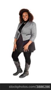 A full body picture of a young African American woman in a black dressand grey jacket and boots, standing isolated for white background.