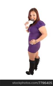 A full figured young woman in a purple dress and boots eating a holechocolate bar, smiling and with red hair for white background.